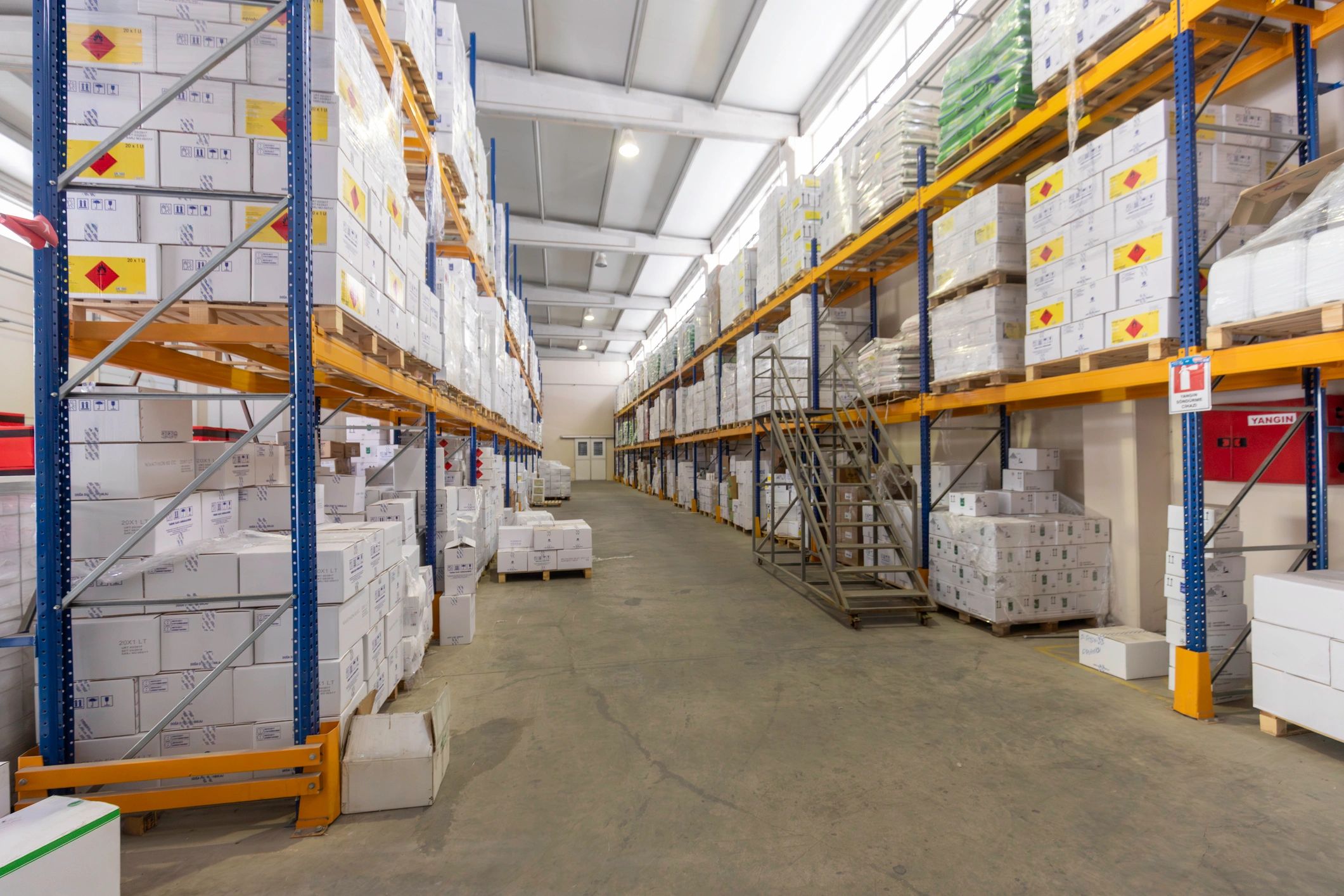 Warehouse aisle with shelves stacked with boxes and a staircase